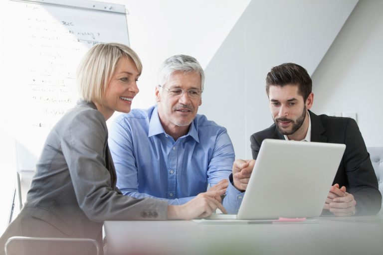 People around a laptop looking at the screen, pointing