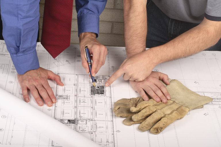 4 hands pointing at an architectural diagram on a table